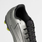 Close-up of a silver soccer cleat with black laces and neon yellow studs visible at the heel edge