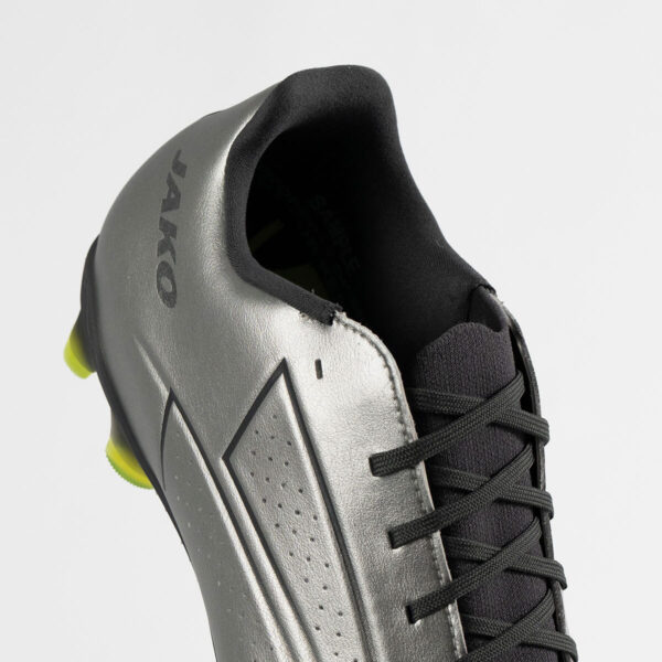 5552_677_P03 Close-up of a silver soccer cleat with black laces and neon yellow studs visible at the heel edge
