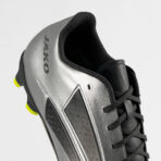 Close-up of a silver and black athletic shoe, showing laces and neon yellow outsole accents in the heel area.