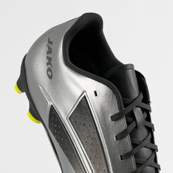 5553_677_P03 Close-up of a silver and black athletic shoe, showing laces and neon yellow outsole accents in the heel area.