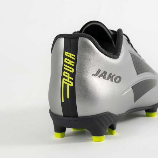 5553_677_P06 Close-up of a silver soccer cleat heel with a black vertical stripe and neon yellow studs, branded JAKO on the side.