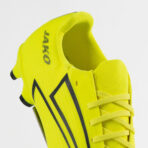 Close-up of a neon yellow soccer cleat with black branding, showing the laces and textured upper from a side view