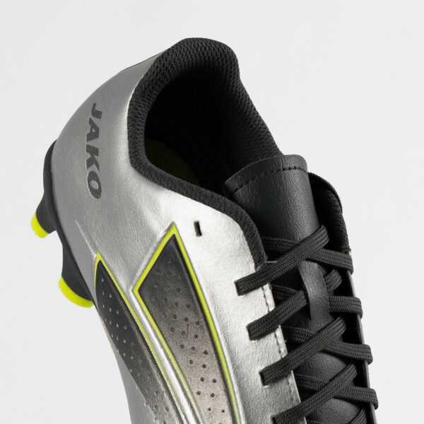 5555_677_P03 Close-up of a silver soccer cleat with black laces, perforated side panel, and lime-yellow trim; brand text visible on the heel.