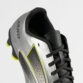 Close-up of a silver soccer cleat with black laces, perforated side panel, and lime-yellow trim; brand text visible on the heel.