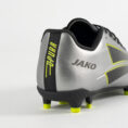 Rear view of a silver soccer cleat with neon yellow accents and the Jako logo on the heel area.